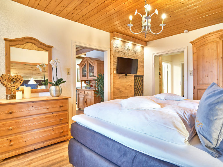 Schlafzimmer mit Fernseher und Boxspringbett in der Ferienwohnung Arbersee in Bodenmais